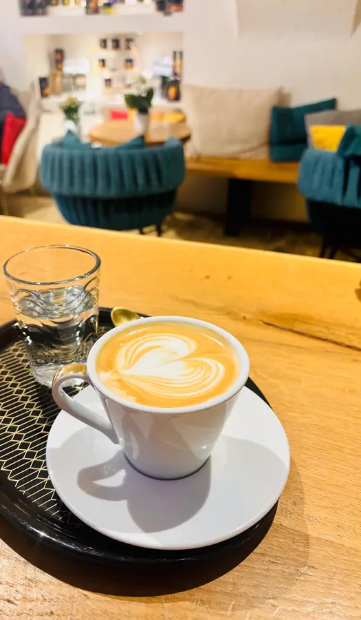 Cappuccino mit Herz-Latte-Art auf einem schwarzen Tablett