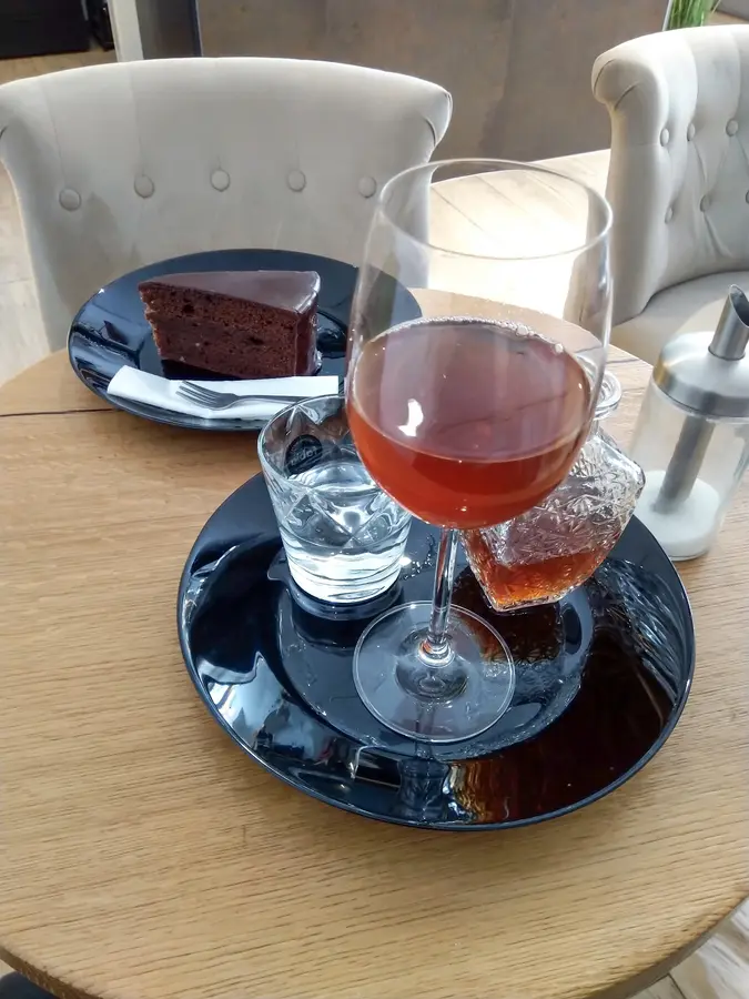 Schokoladekuchen und ein Getränk im Weinglas auf einem Holztisch